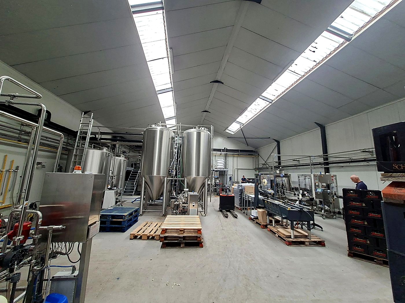Interior of the Belgian brewery, showing stainless steel fermentation tanks and the bottling line